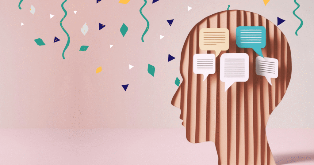 Para representar a neurociência da comunicação, uma ilustração de perfil de uma cabeça humana em papelão ondulado com balões de fala flutuantes e confetes coloridos em um fundo rosa claro, simbolizando ideias, pensamento ativo e comunicação.