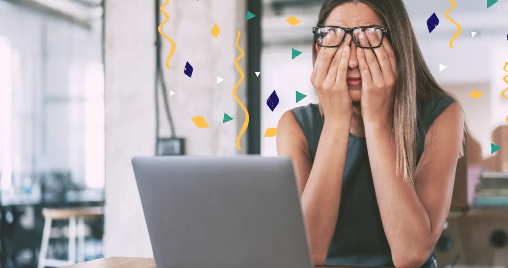 Para representar a ressaca corporativa, uma mulher sentada em sua mesa de trabalho com a cabeça apoiada nos braços, cercado por confetes espalhados, sugerindo exaustão após celebração ou esforço intenso no trabalho.